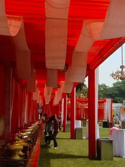 This is a view of the catering section under a large red and white tent at a daytime event. I ensure all parts of the event space are well-decorated and functional.
