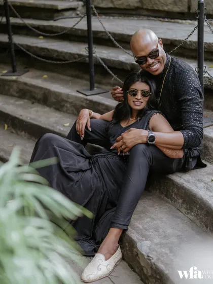 A modern, chic couple in matching black outfits, seated on the stone steps for a cool, contemporary-style portrait.