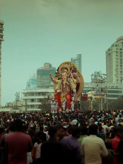 Another perspective of the visarjan, with a large idol framed against the modern buildings of Mumbai, showing the blend of tradition and city life.