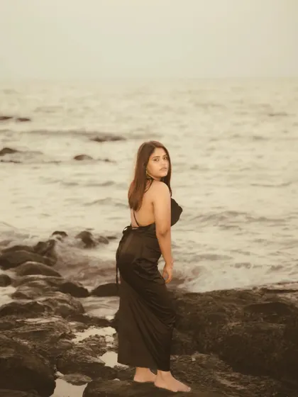 A duplicate of image 9, this sepia-toned portrait on a rocky beach captures a feeling of quiet contemplation. The monochromatic feel adds to the timeless, artistic quality of the shot.