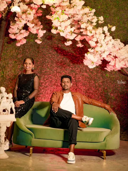 A relaxed pose on a green sofa against a backdrop of cherry blossoms. This indoor setup is both elegant and comfortable.