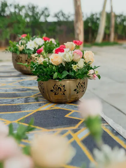 Small brass bowls with lotus cutouts, filled with fresh roses, are placed along the aisle. It is these small, thoughtful details that elevate the entire guest experience.