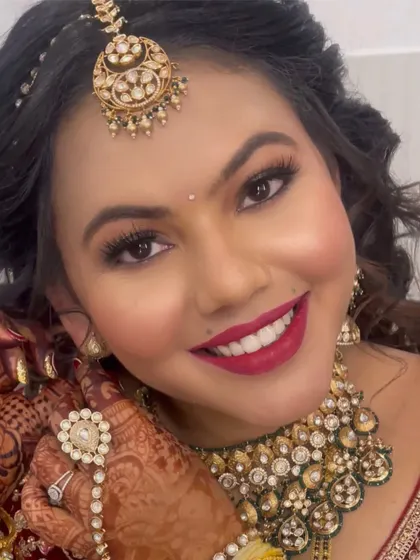 A close-up of this radiant bride. Her look features a bold red lip, shimmering gold eyeshadow, and flawless skin, perfectly complementing her red velvet lehenga and kundan jewellery.