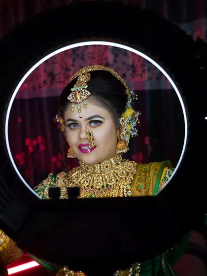 A vibrant bridal portrait taken through a ring light, perfectly framing her face and showcasing her stunning gold jewelry and makeup.