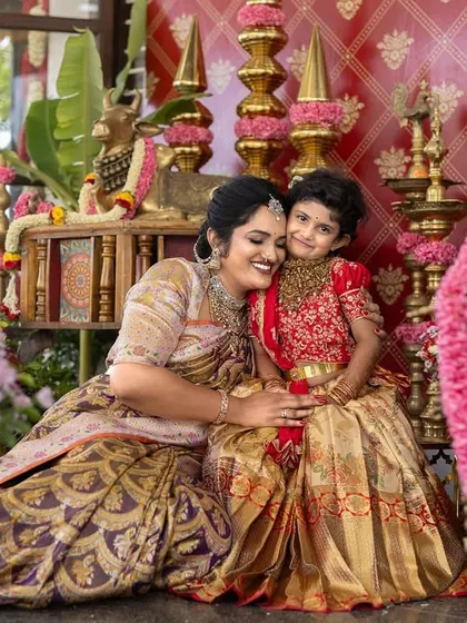 A mother and daughter sharing a hug in a beautifully decorated setting for an ear piercing ceremony, surrounded by flowers.