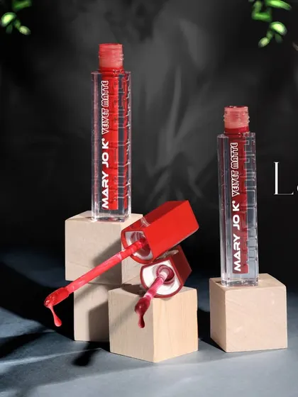 A creative flat lay of nail lacquer bottles with drips and brushes, showcasing the product's color and texture in an artistic way.