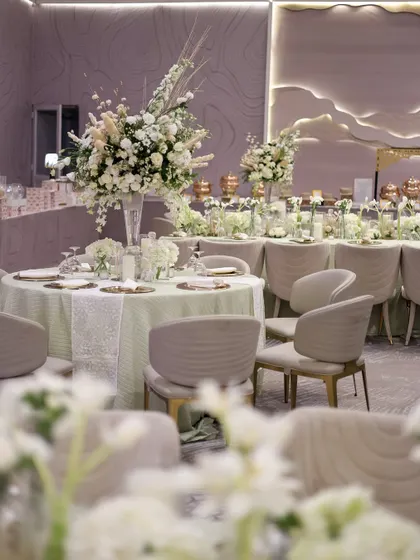 The guest dining tables featured tall, dramatic floral arrangements and modern, comfortable seating in a soft, neutral palette.