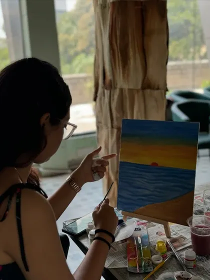 A participant painting a beautiful sunset over the ocean. Canvas painting is a classic way to relax and create.
