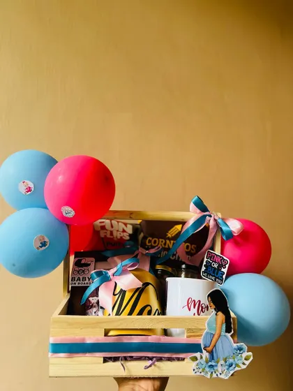 Holding up a completed mom-to-be gift hamper. The wooden crate is easy to carry and makes for a wonderful presentation at a baby shower.