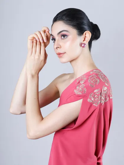 A side profile of a model in a pink one-shoulder dress, showcasing the garment's fit and the model's poised look for a portfolio.