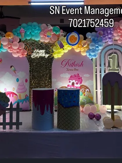 A sweet Candyland theme for a first birthday. This decoration features ice cream and candy props, a pastel balloon arch, and a glittery gold backdrop for a delicious-looking party.
