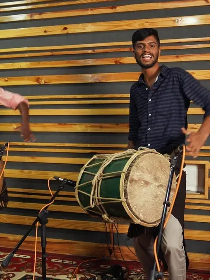 Two Dollu players from Sagara, smiling and ready to play. The studio is a place of joy and excitement, not just serious work.