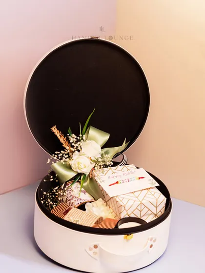 Another view of the versatile and reusable white leather Rakhi box, beautifully adorned with a floral arrangement and ribbon. The packaging is a gift in itself.