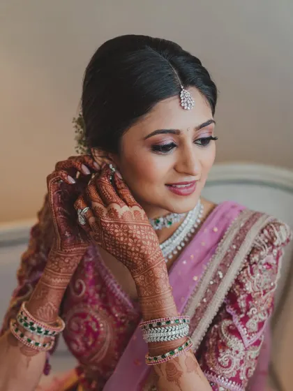 The final touches. This image captures the intricate details of her makeup and jewelry, showing how every element works in harmony to create the perfect bridal look.
