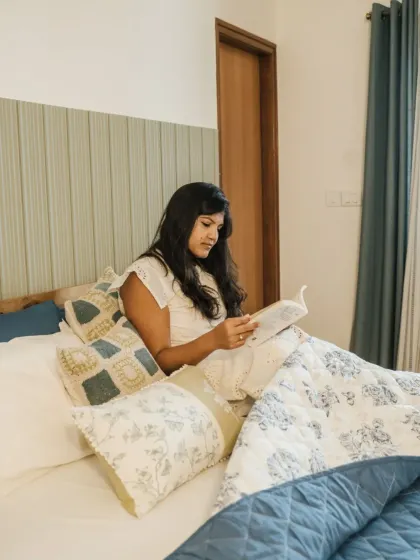 A happy client enjoying a quiet moment in her newly styled bedroom. The bed is layered with our custom quilt and a mix of our printed and textured cushion covers, creating a personal and comfortable retreat.