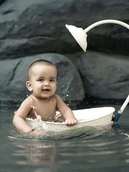This little sailor is enjoying a gentle splash in his boat. The rocky background adds a nice, natural texture to the photo.