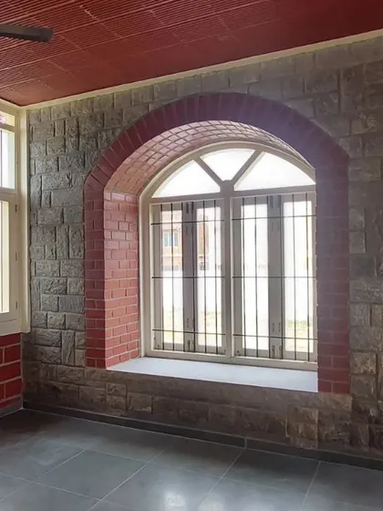 A beautiful arched window set within a stone wall, with a brick arch providing a contrasting frame.