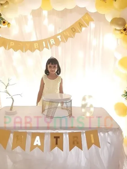 A simple and sweet yellow and white themed party with a birthday girl posing by the cake table.