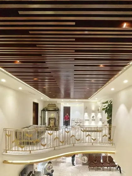 A view from the upper level of the 902 Residence, showing the double-height living space. The curved balcony with its intricate railing overlooks the main hall, while a wooden batten ceiling adds warmth and texture.