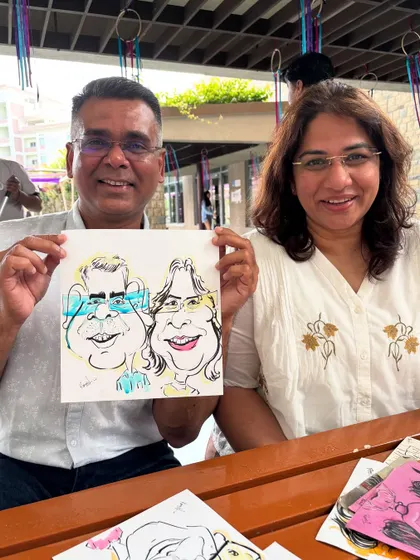 This couple is all smiles with their caricature, a great memory from their alumni reunion.