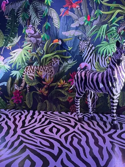 Welcome to the jungle. I created this immersive sanctuary with a custom illustrated backdrop, zebra-print flooring, and life-sized animal props to transport guests into a vibrant, tropical world.