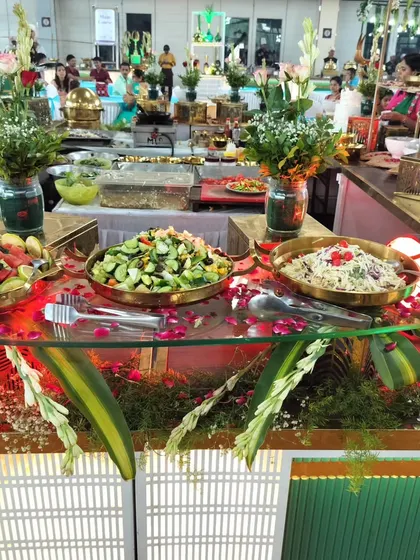 A vibrant buffet counter filled with a variety of fresh salads and main courses, part of a large-scale catering event.