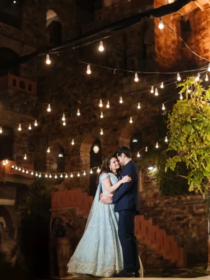 A fairytale first dance under a sky of twinkling lights. This frame captures the romance and magic of a sangeet night at the historic Fort Neemrana, surrounded by the warmth of family and friends.