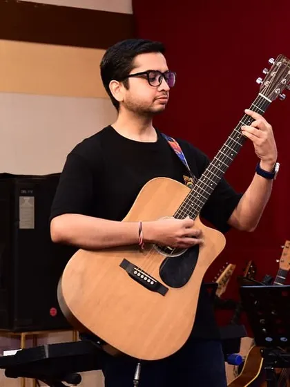 A student confidently performs a piece on his acoustic guitar at our concert. The stage is where all the hard work and practice come to life.