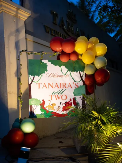 A welcome sign for "Tanaira's Wild Two" party, adorned with Lion King characters and balloons, greeted guests for an evening of jungle fun.