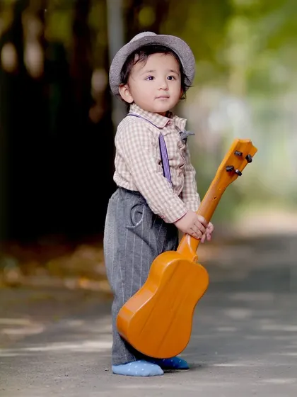 A toddler stands on a path holding a small guitar, a great prop for adding a playful element to outdoor kids' photography.