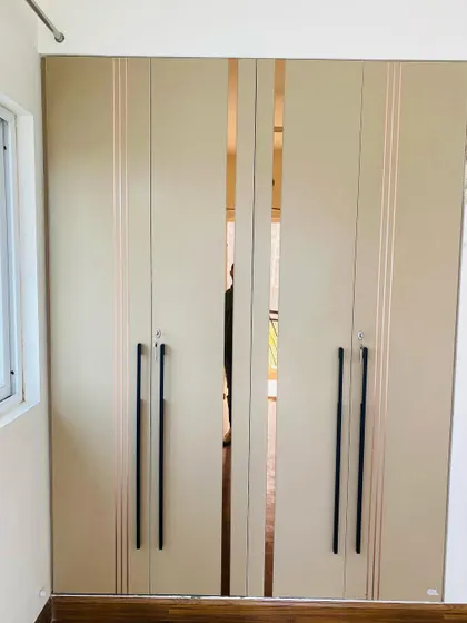 A four-door wardrobe with long black handles and rose gold mirror strips for a touch of glamour.