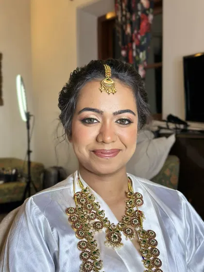 A close-up of the bridal preparation. Even before the saree is draped, the makeup provides a flawless, glowing base that promises a stunning final look.