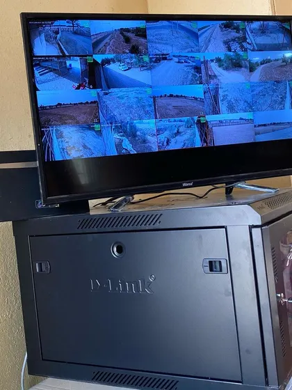 A finished setup with a D-Link server rack and a monitor showing a 16-camera view of an outdoor property.