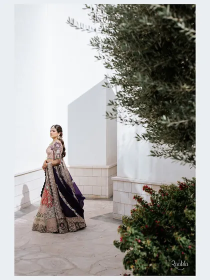 A beautiful bridal portrait in Doha, with the bride framed by an olive tree and modern white architecture.