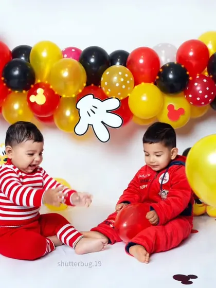 Twin boys having a blast playing with balloons during their fun and colorful Mickey Mouse themed photoshoot.