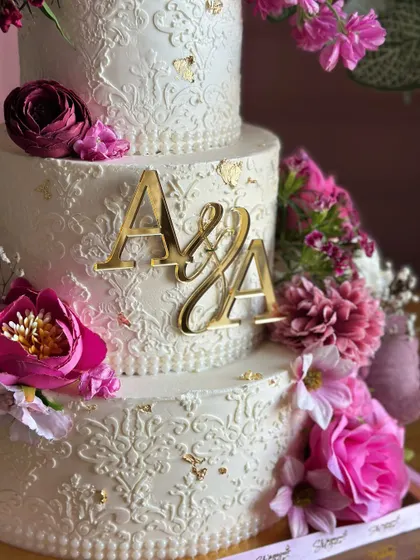 This exquisite three-tiered engagement cake features a pristine white finish with delicate, hand-piped details. A cascade of exotic, vibrant flowers adds a perfect contrast, symbolizing a love that is both pure and full of life.