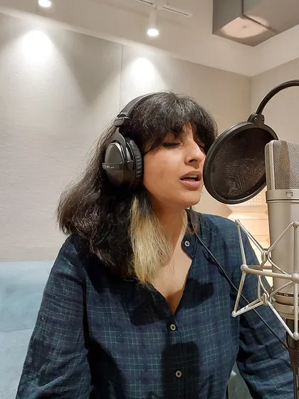 Another shot of a vocal recording session, showing the professional setup with headphones and a pop filter.