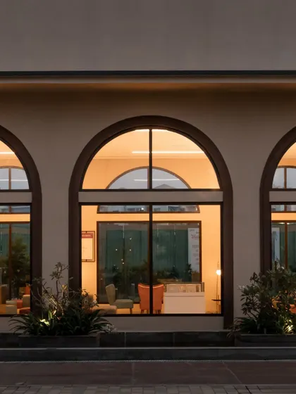 The repetition of the three arches at night creates a powerful visual statement. This detail shot highlights the simple elegance of the facade design at Brigade Valencia.