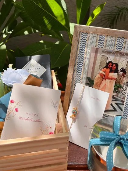 A beautifully composed shot of the sister Rakhi hamper, highlighting the custom photo frame and personalized "Happy Rakshabandhan" card.