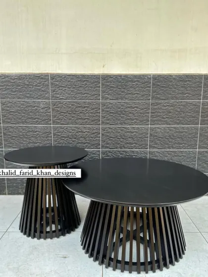 A nested set of two black slatted coffee tables, one larger and one smaller, offering flexible arrangement options.