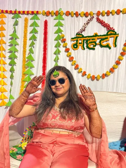 This guest is all smiles, posing with her full-hand mehendi at a vibrant party.