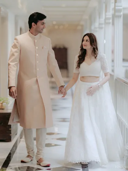 A classic portrait of the couple walking hand-in-hand through a beautiful, light-filled hotel corridor, capturing the elegance of their simple wedding.