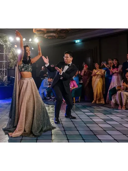 Nick and Shachi do their first dance at the sangeet. Their joyful moves and the cheering crowd create a fun and energetic atmosphere.