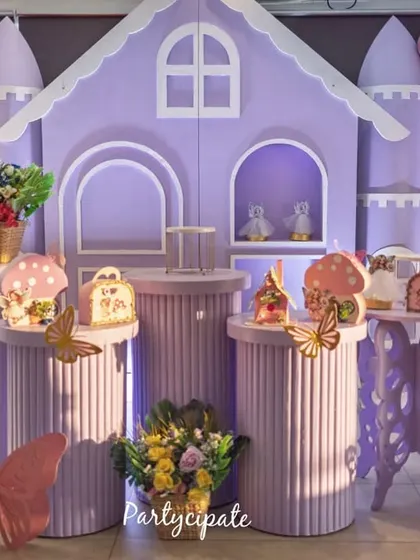 Amayra's fairy garden party featured this lovely purple castle backdrop. We used fluted pedestals for desserts, butterfly cutouts, and a neon '3' to mark her special day, creating a perfect spot for photos.
