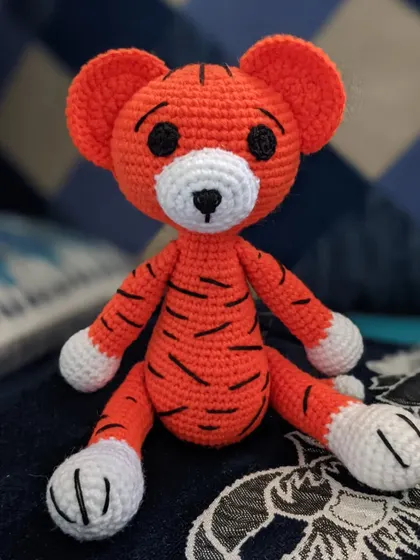The orange tiger toy sitting on a blue patterned surface.