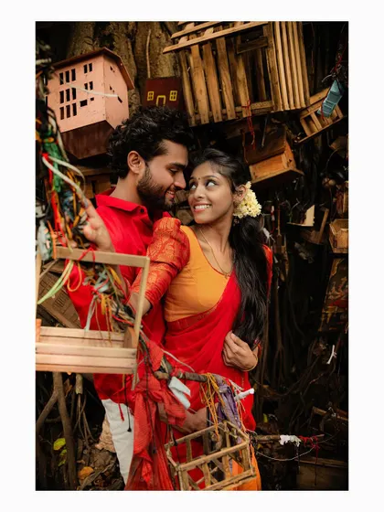 A unique pre-wedding shot with a couple surrounded by miniature wooden houses hanging from a banyan tree.