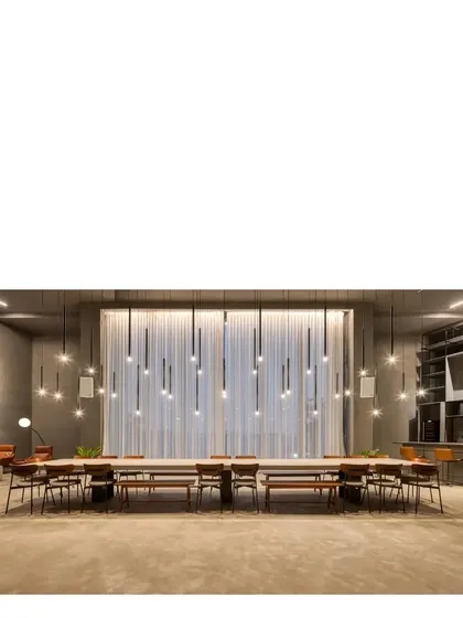 The communal table in our elemental gallery space. The room is designed to be highly adaptable, with seamless gray concrete surfaces and dramatic lighting that can be configured for parties, exhibitions, or gatherings.