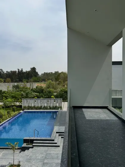 A view from a covered balcony at the Rosewood residence overlooks the expansive pool and the distant tree line. We design these transitional spaces to act as private outdoor rooms, offering shelter while maintaining a strong connection to the landscape.