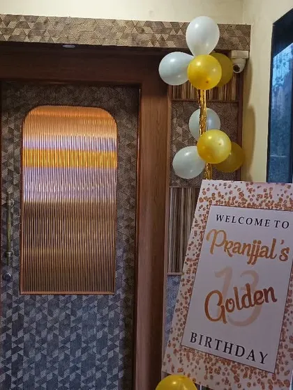 The entrance decor for a 13th birthday, featuring a custom "Golden Birthday" welcome sign and simple balloon bunches.