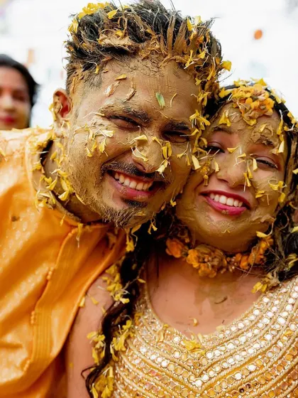 A candid close-up of the couple, faces smeared with Haldi and joy, capturing the raw happiness of the moment.